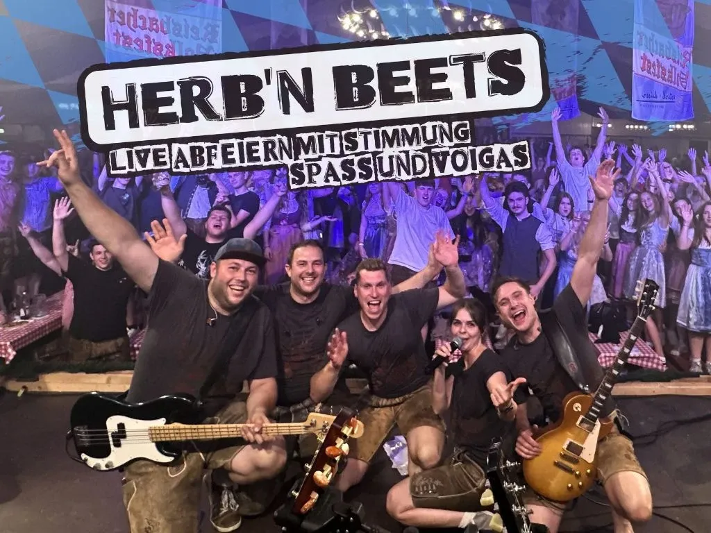 Live-Auftritt der Band Herb'n Beets im Festzelt mit jubelndem Publikum, fünf Musiker in Lederhosen vor blauem Lichtschein