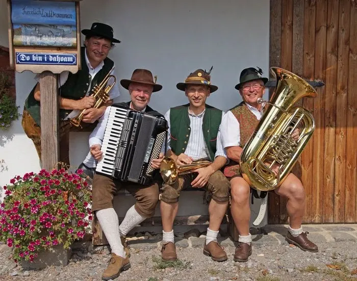 VorwaldBlech: vier Männer in Tracht vor einer Holzhütte mit Trompete, Akkordeon, Waldhorn und Tuba