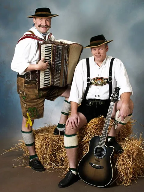 Original Oberpfalz Duo: zwei Männer in Tracht auf Strohballen mit Akkordeon und Gitarre