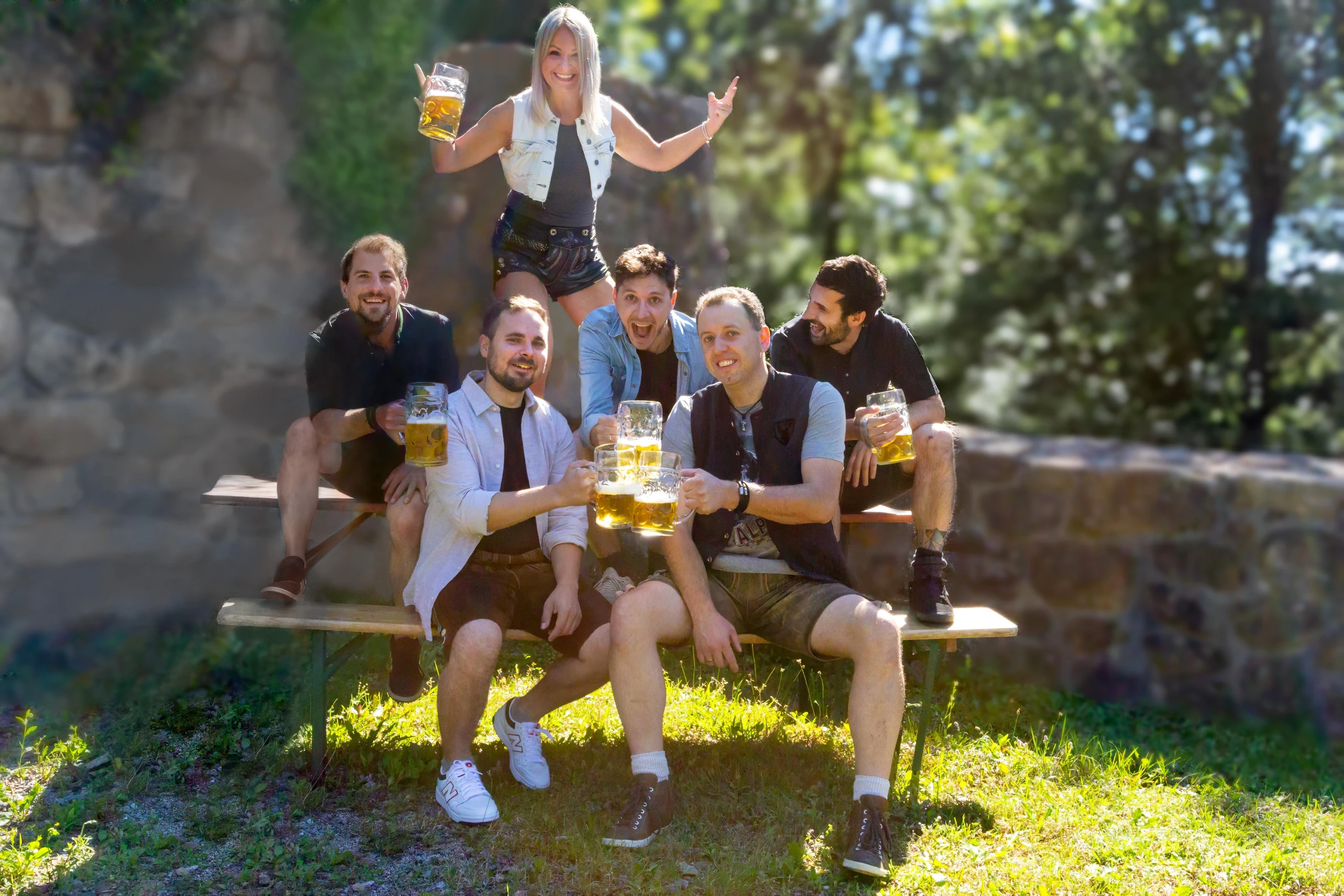 Sechs Musiker der Kasplattnrocker mit Bierkrügen auf einer Holzbank im Freien