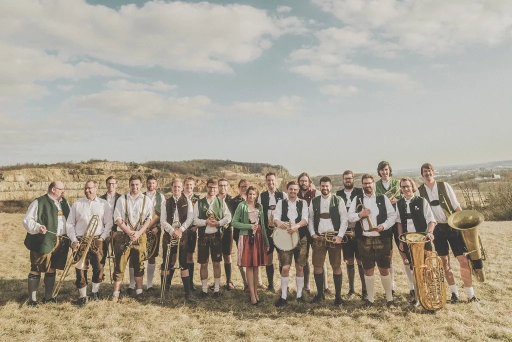 Festkapelle Regensburg in Tracht mit Blechblasinstrumenten auf einer Wiese vor Felsen
