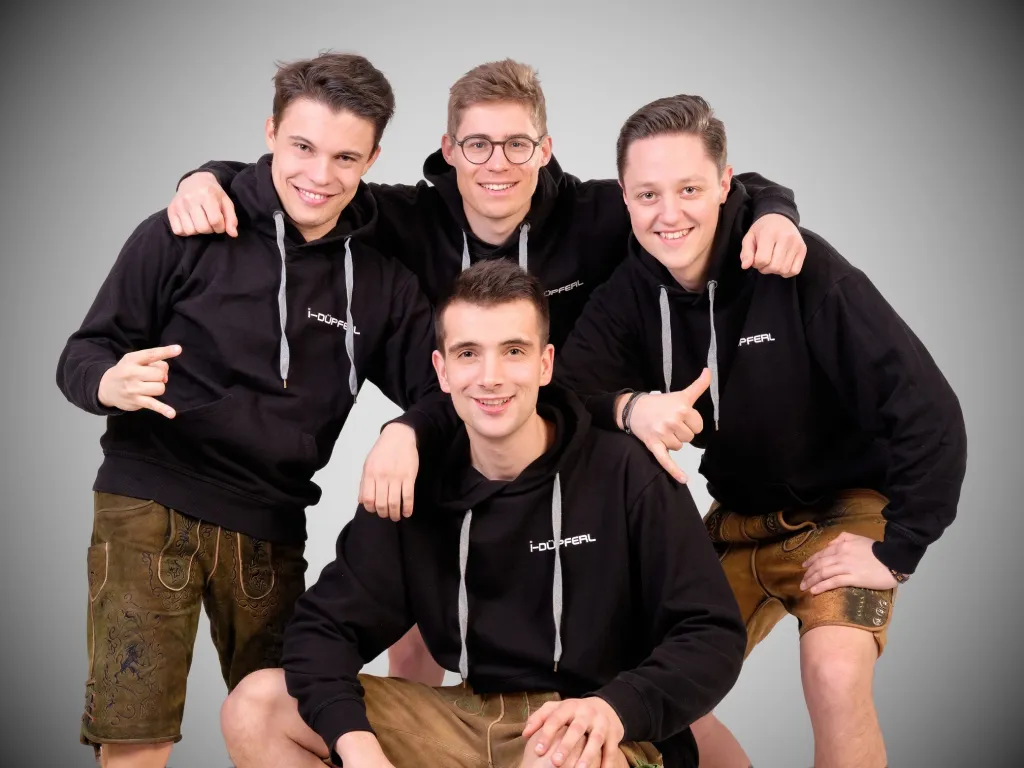 Vier junge Männer der Band i-Düpferl in schwarzen Hoodies und Lederhosen