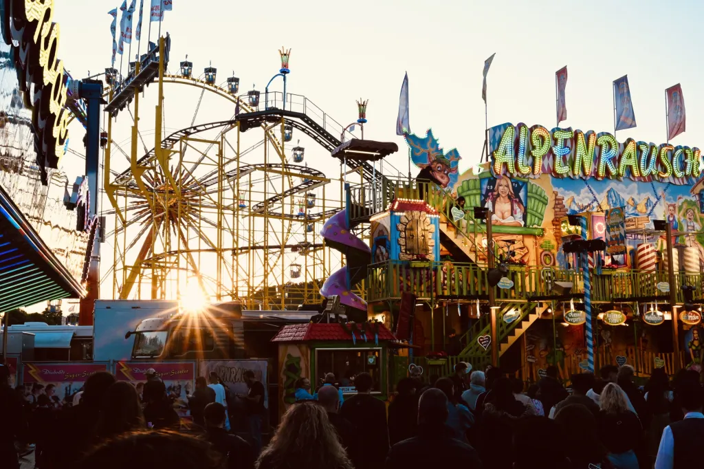 Achterbahn Alpenrausch und Riesenrad bei Sonnenuntergang auf der Dult
