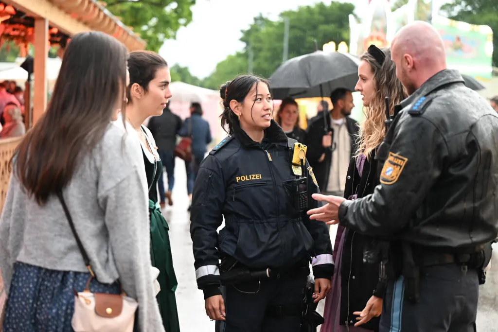 Polizistin im Gespräch mit jungen Besucherinnen auf der Dult bei Regenwetter