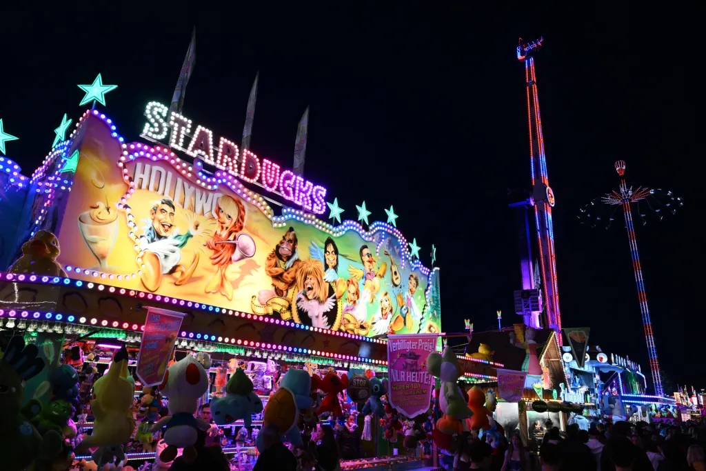 Bunt beleuchtete Stardogs-Schießbude bei Nacht mit Plüschtier-Auslage