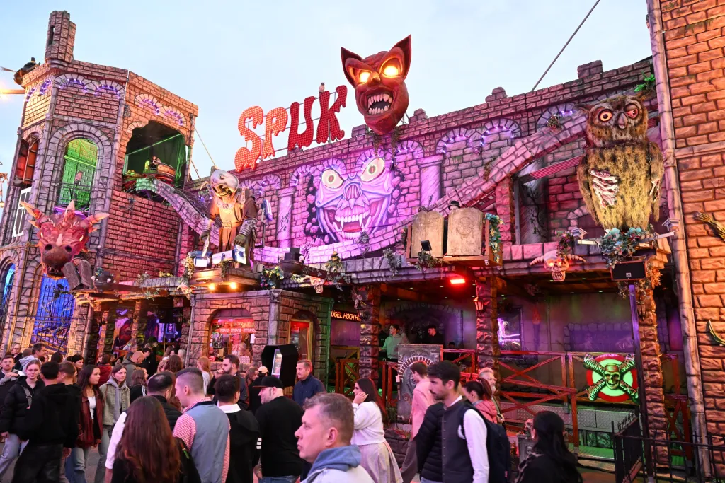 Gruselkabinett Spuk mit beleuchteter Fledermaus-Fassade und Besuchern davor bei Nacht