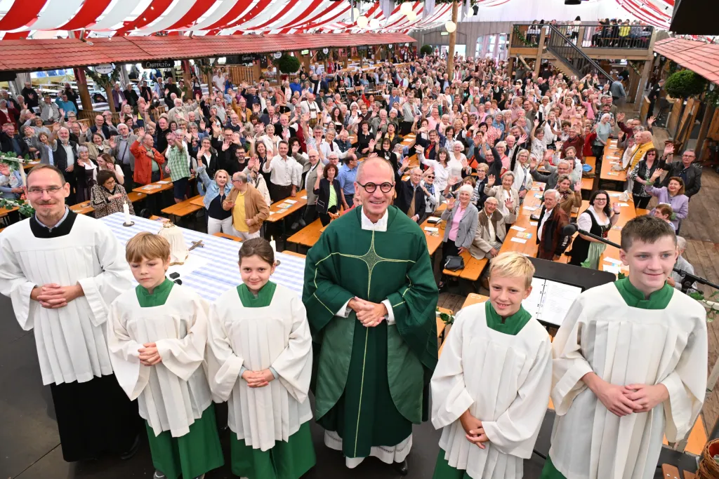Pfarrer mit Ministranten im Festzelt vor jubelnder Gemeinde beim Dult-Gottesdienst