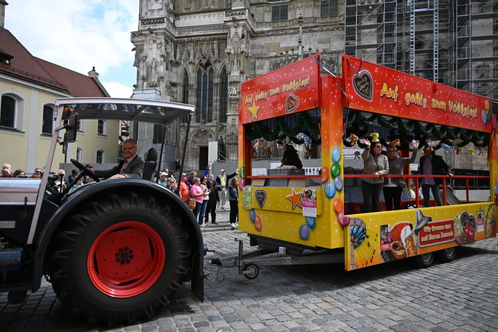 Geschmückter Festwagen mit Traktor und Schaustellern fährt am Regensburger Dom vorbei