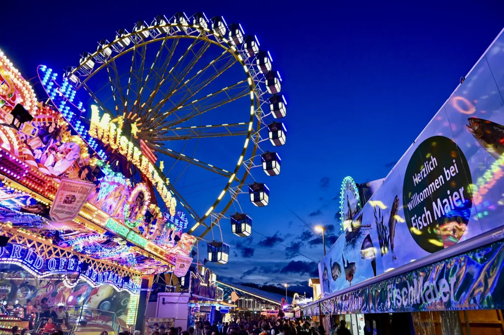Beleuchtetes Riesenrad und Fisch-Maier-Stand bei Abenddämmerung auf der Maidult