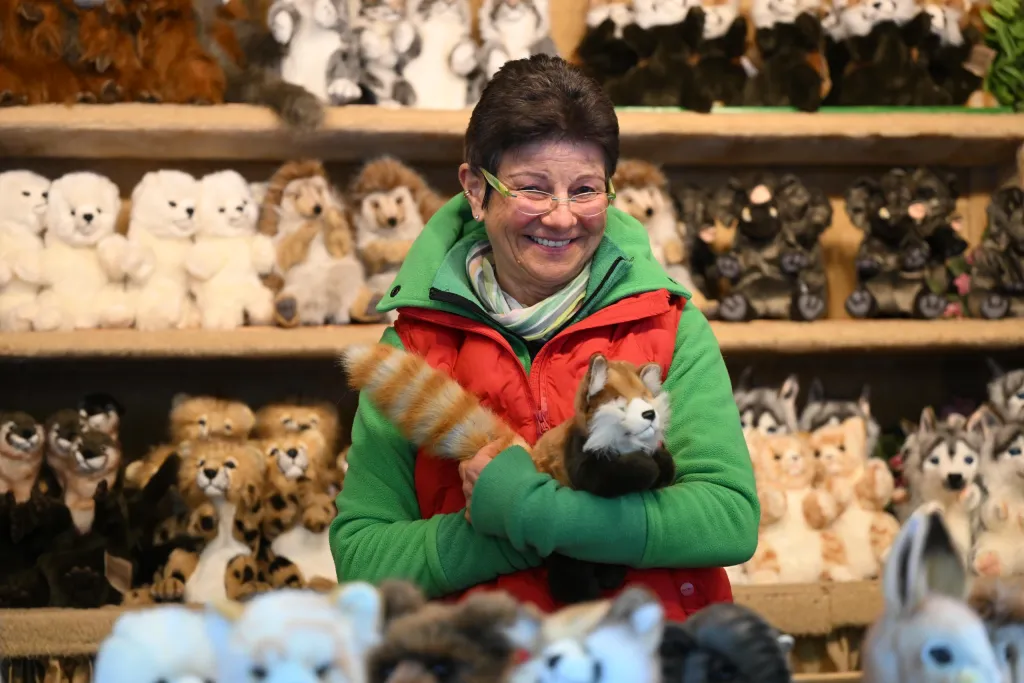 Verkäuferin im grünen Pullover hält Plüsch-Eichhörnchen vor Regalen mit Stofftieren