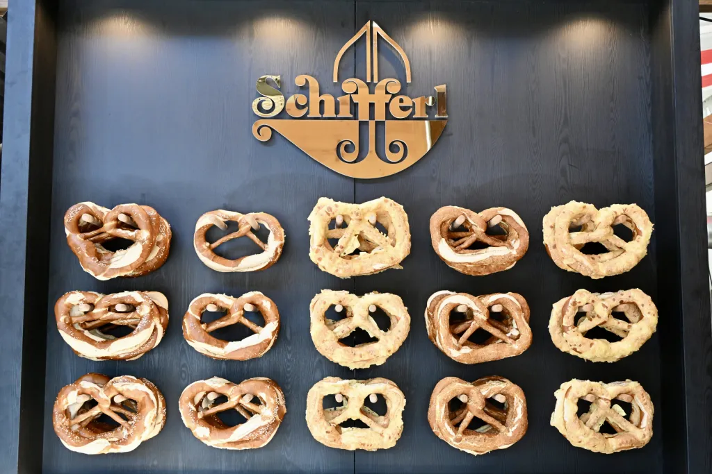 Brezen in Reihen an dunkler Wand unter Schiffert-Schriftzug der Brezenbäckerei