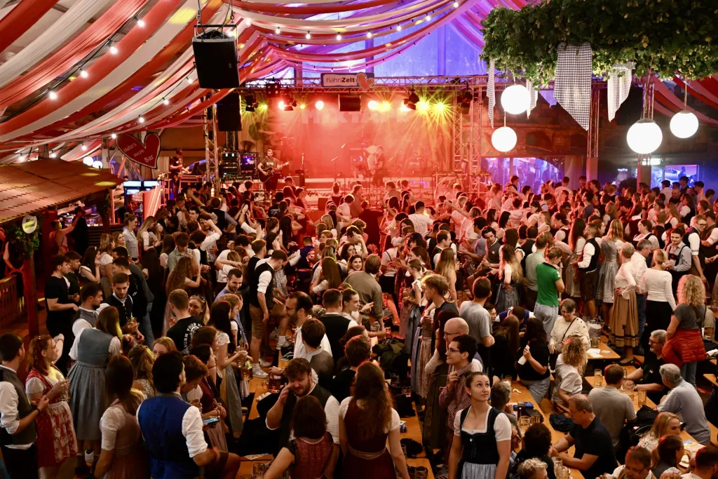 Tanzende Menschenmenge im Festzelt vor beleuchteter Bühne bei Livemusik