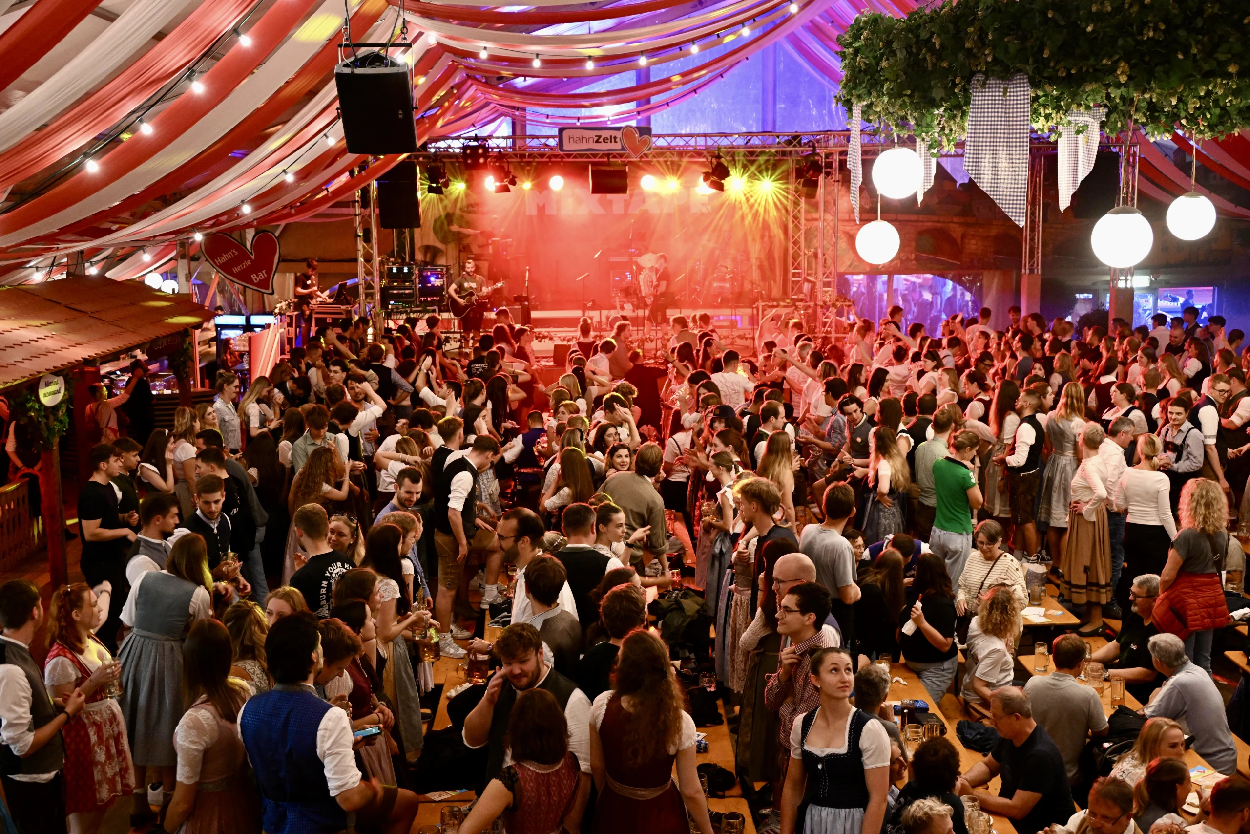 Tanzende Menschenmenge im Festzelt vor beleuchteter Bühne bei Livemusik