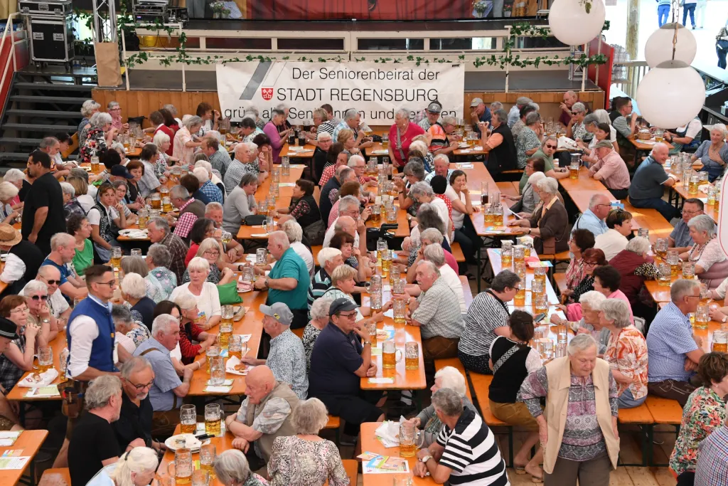 Seniorennachmittag im Festzelt mit vielen Gästen an geschmückten Bierbänken vor Transparent