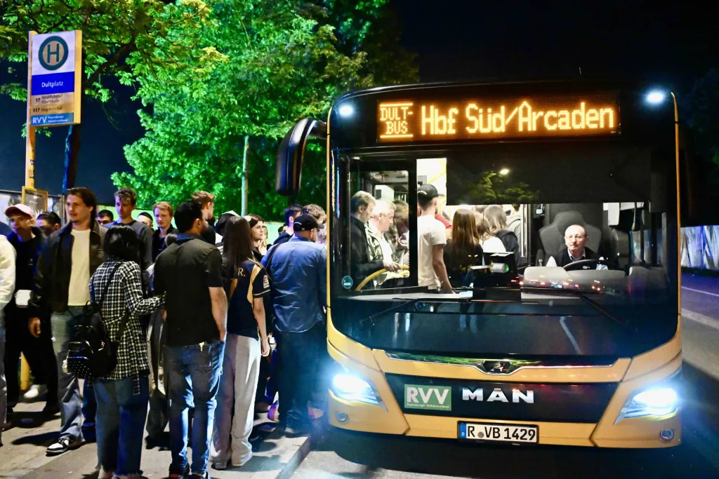 Beleuchteter Dult-Shuttlebus am Haltepunkt Galgenberg in Richtung Hauptbahnhof bei Nacht