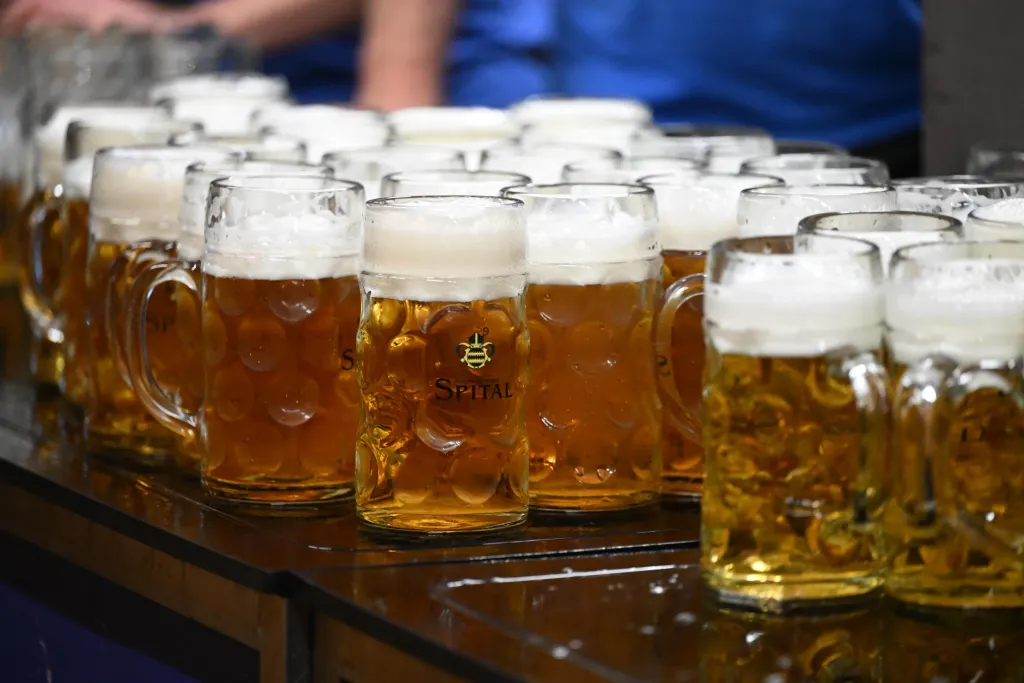 Reihe gefüllter Maßkrüge mit Spital-Bier und dicker Schaumkrone auf einer Theke im Festzelt