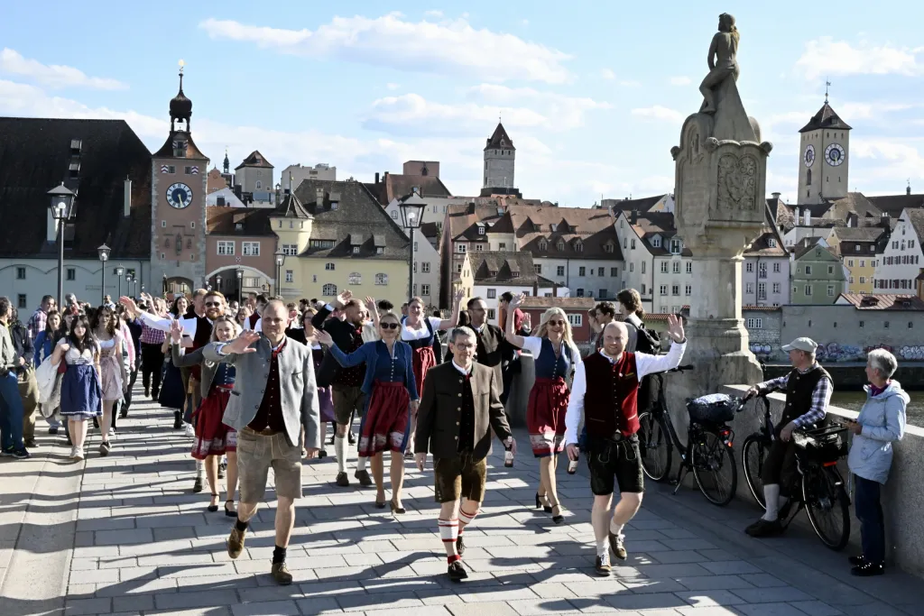 Festzug in Tracht über die Steinerne Brücke mit Brückturm und Regensburger Altstadt