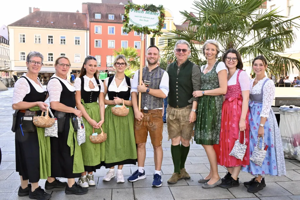 Trachtengruppe und Festwirt mit Bierkrug-Pokal vor Regensburger Altstadtkulisse
