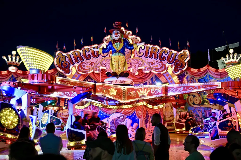 Beleuchtetes Fahrgeschäft Circus Circus mit Clownsfigur bei Nacht
